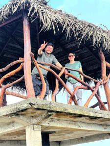 two people sitting on top of a thatched roof at Jm Resort in Dambulla