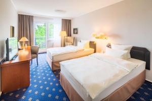 a hotel room with two beds and a desk at Best Western Hotel Windorf in Leipzig