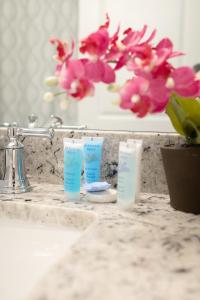 a bathroom sink with two bottles of toothpaste and flowers at Sea Lion Serenity Retreat - New Construction 2024 in Port Saint Lucie