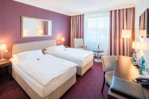 a hotel room with two beds and a desk at Best Western Hotel Hamburg International in Hamburg