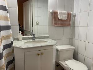 Un baño blanco con inodoro y lavabo. en Luigi's Apart Hotel, en Santiago