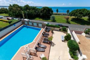 an overhead view of a swimming pool with chairs and the ocean at Logis Hôtel Le Rochelois in La Rochelle