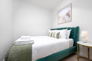 a bedroom with a bed with a green headboard at Luxury apartment free car park, pool, gym, Sauna, steam room in Melbourne