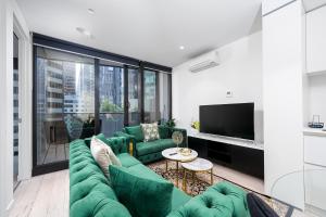 a living room with a green couch and a tv at Luxury apartment free car park, pool, gym, Sauna, steam room in Melbourne