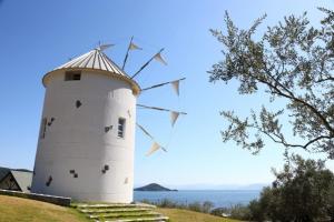 a white windmill on top of a hill with the ocean at Precious Hotel 綾川 in Ayagawa