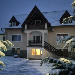 una casa nella neve di notte di Pensiunea CORIMEN Vadu Crisului a Vadu Crişului