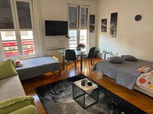 una sala de estar con dos camas y una mesa en Apartman u Pašićevoj, en Novi Sad