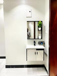 a white bathroom with a sink and a mirror at Sn Suites apartment in Kampala