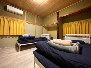 two beds in a room with yellow curtains at Puka Puka 1組限定 in Oshima