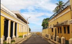蓬蒂切里The Muthu Beach Resort的一条空的街道,有黄色的建筑和棕榈树