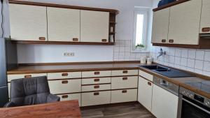 a kitchen with white cabinets and a chair in it at Ferienwohnung Küffner in Hollfeld