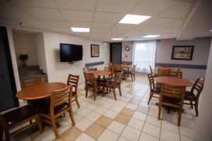 a dining room with tables and chairs and a flat screen tv at Super 8 by Wyndham Whitecourt in Whitecourt