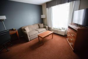 a living room with a couch and a chair and a television at Super 8 by Wyndham Whitecourt in Whitecourt