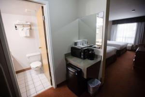 a hotel room with a bathroom with a bed and a microwave at Super 8 by Wyndham Whitecourt in Whitecourt