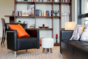 a living room with a couch and a book shelf at Best Western Macrander Hotel Dresden in Dresden