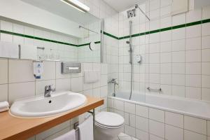 a bathroom with a sink and a toilet and a tub at Best Western Macrander Hotel Dresden in Dresden