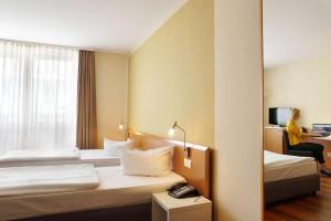 a hotel room with two beds and a woman sitting in a chair at Best Western Macrander Hotel Dresden in Dresden +64 photos