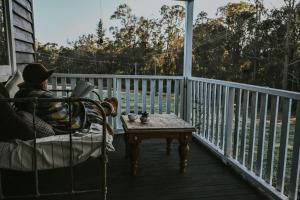 a person sitting in a chair on a porch with a table at Two Brothers' Cabin in Deeside