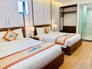 a hotel room with two beds and a mirror at Aloha Hotel in Quy Nhon
