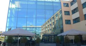 two tables and umbrellas in front of a building at Best Western Premier Novina Hotel Regensburg in Regensburg