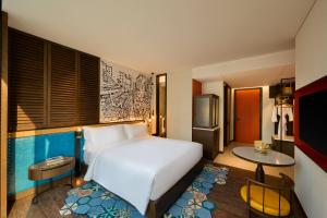 胡志明市Hotel Indigo Saigon the City by IHG的卧室里有一张白色的大床和一台冰箱