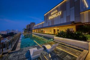 胡志明市Hotel Indigo Saigon the City by IHG的一座大楼前的游泳池,配有两把椅子