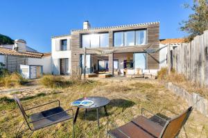 a house with a table and chairs in the yard at 6 adultes et 2 enfants - piscine et accès plage direct in La Guérinière