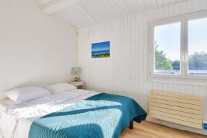 ein weißes Schlafzimmer mit einem Bett und einem Fenster in der Unterkunft À 300m de la plage, maison pour 6 personnes in La Guérinière