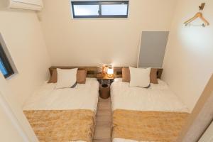 two beds in a small room with a window at RIAUS 新築一軒家貸切 最大6名 family歓迎 空港や観光地直通 in Tokyo
