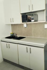 a white kitchen with a sink and a microwave at Rest Inn C Guesthouse - 10min from OR Tambo Airport in Boksburg