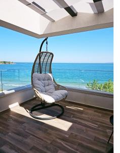 Olive Villas Beach Hotel في سوزوبول: كرسي يتأرجح في غرفة مطلة على المحيط