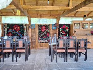 a dining room with tables and chairs and a kitchen at Casa Gramy in Neagra Şarului