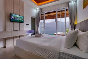a bedroom with a large white bed and a television at Villa Moana - Nusa Dua in Nusa Dua +22 photos