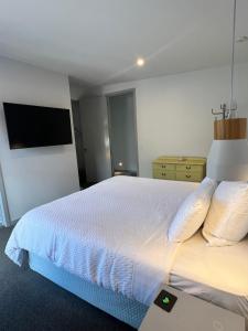 a bedroom with a large bed with a tv on the wall at Golden Hour Villa in Queenstown