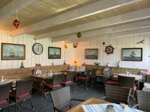 a dining room with tables and chairs and a clock at Pension Windrose in Prerow