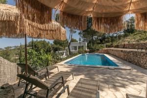 a swimming pool with chairs and umbrellas and a swimming poolvisor at Sunset villa with pool and seaview in Cala Tarida