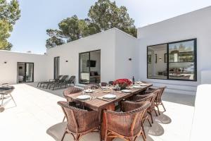 an outdoor patio with a wooden table and chairs at Sunset villa with pool and seaview in Cala Tarida