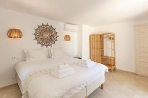 two white beds in a white bedroom with a mirror on the wall at Sunset villa with pool and seaview in Cala Tarida +34 photos