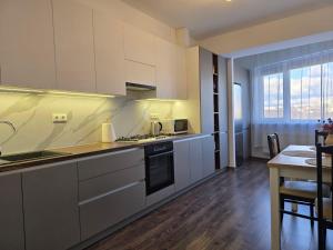 a kitchen with white cabinets and a table and a dining room at Spacious & Cozy Apartment in Chişinău