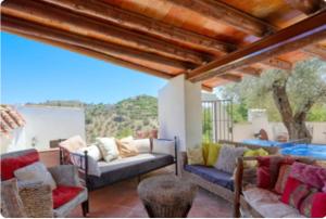 ein Wohnzimmer mit einem Sofa und Stühlen auf einer Terrasse in der Unterkunft Cortijo Cuscurro in Ríogordo