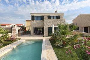 a house with a swimming pool in front of a house at Villa Stella with heated swimming pool in Privlaka