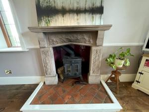 a stone fireplace with a stove in a room at Idyllic Historical Country Retreat in Elkstone - Pass the Keys in Warslow