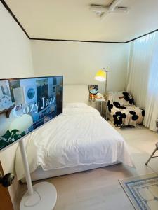 Un dormitorio con una cama blanca con un panel de vacas en la pared en Cozy guesthouse, 10 minutes from SNU Entrance Station, accommodation in Sharosu-gil, OTT, Nespresso machine, within 25 minutes by subway to Hongdae, Gangnam, Seongsu, Gwanaksan, up to 5 people, en Seúl