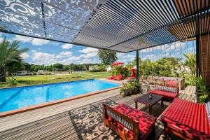 a patio with a pool and a deck with red chairs at The Campster Kanchanaburi in Kanchanaburi City