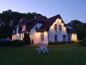 a white house with a table and chairs in the yard at Ferienhof Johannsen Ferienwohnung Gartenblick in Gelting