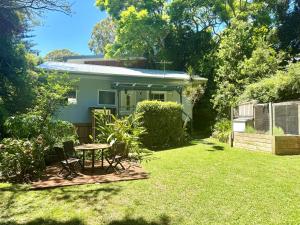 ein Haus mit einem Tisch und Stühlen im Hof in der Unterkunft Seabreeze Cottage Bundeena in Bundeena
