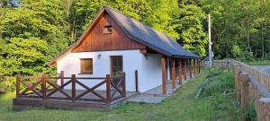 a small house with a wooden roof and a fence at Chalupa u Uhříků in Rajnochovice
