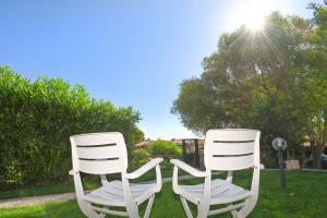 two white chairs sitting in the grass with the sun in the background at Villa Gioia in Costa Rei