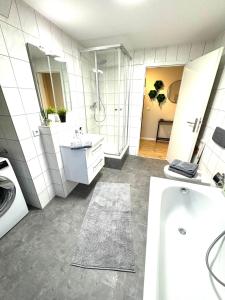 a white bathroom with a tub and a sink at Gästeapartment Schkeuditz in Schkeuditz