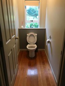 a bathroom with a toilet with a window at Cozy FarmStay with Spa in Pokeno +7 photos